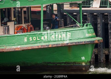 Un membro dell'equipaggio si trova a poppa della "Stella polare", una delle flotte di Star Ferry, mentre lascia il molo 7 del Central Ferry, Isola di Hong Kong Foto Stock