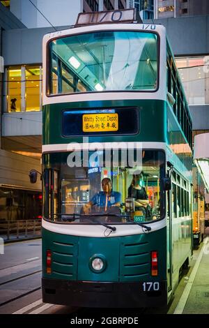 Uno dei tre tram del 'millennio' (costruito nel 2000) nella flotta su Des Voeux Road, Central, Isola di Hong Kong, al crepuscolo Foto Stock