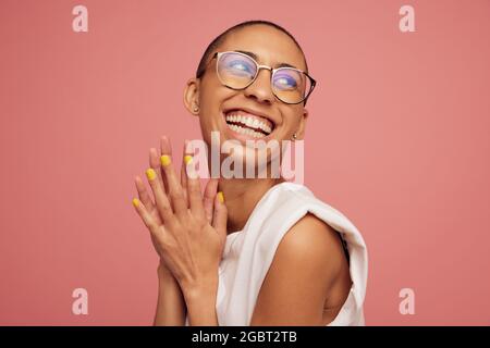 Donna con testina rasata che guarda lontano e sorride. Femmina sorridente con capelli corti che indossano occhiali da vista. Foto Stock