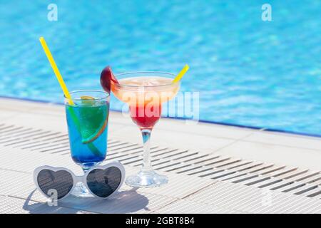 Due colorati bicchieri da cocktail ai bordi della piscina. Con spazio per la copia Foto Stock