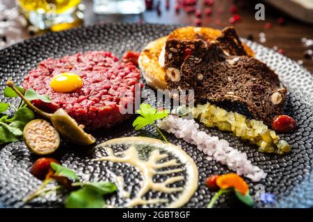Tartare di manzo da Black Angus. Cipolla, uova di quaglia, salsa di pomodoro, maionese di senape. Delizioso e salutare primo piano di cucina italiana tradizionale servito per pranzo Foto Stock