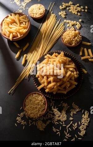 Diversi tipi di pasta cruda in piatti, ingredienti alimentari sani sfondo Foto Stock