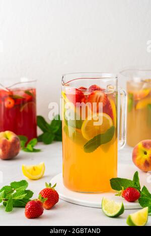 Brocche di fresche bevande alla frutta con spicchi di frutta, succhi estivi freddi con ghiaccio Foto Stock