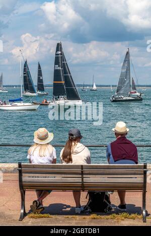 settimana dei cowes, isola di wight, tre persone in panchina, tre spettatori che indossano cappelli, regata di vela, eventi di yacht, tre persone sedute su una panchina. Foto Stock