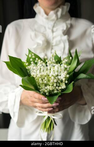 Ragazza che tiene in mano un mazzo di gigli della valle Foto Stock