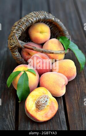 Frutta di pesca matura appena prelevata su un vecchio tavolo di legno, fuoco selettivo nella parte inferiore dell'immagine. Il concetto di giardinaggio organico. Foto Stock