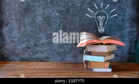 libri e lavagna con disegno di una lampadina, istruzione, apprendimento, lettura, idea, concetto di creatività, grande spazio di copia Foto Stock