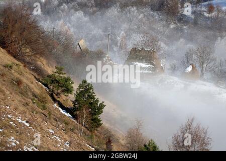 Nebbia e sole nel villaggio di montagna Foto Stock