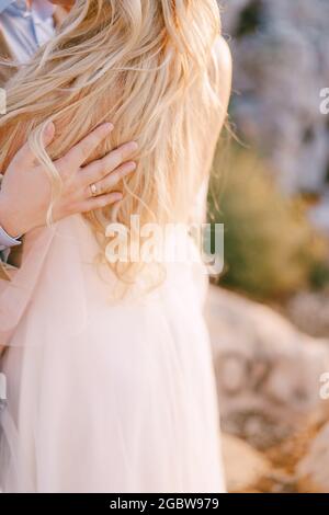 La mano dello sposo giace sulla spalla della sposa in un abito bianco. Primo piano Foto Stock