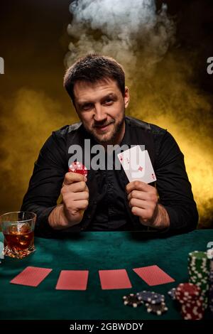 Uomo giocatore di casinò bearded che gioca a poker su tavolo verde Foto Stock