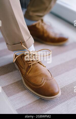 Brogues marroni allacciate sulle gambe dello sposo. Primo piano Foto Stock