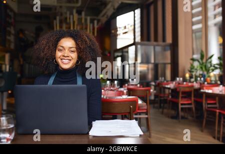 Ritratto di allegro proprietario di ristorante con computer portatile Foto Stock