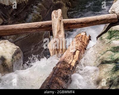 I tronchi si trovano in un fiume schiumoso e tempestoso con rive rocciose ricoperte di limo Foto Stock