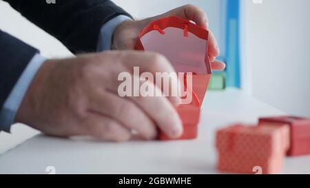 Preparare un regalo per un compleanno in un negozio di articoli da regalo, mettendo piccole scatole regalo in una borsa di carta colorata. Foto Stock
