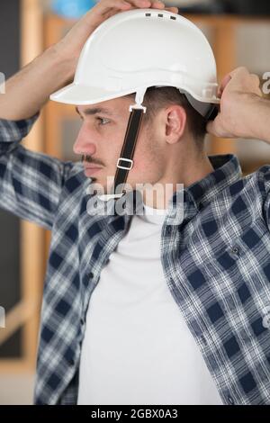 uomo che fissa il suo elmetto alla testa Foto Stock