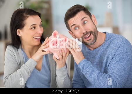 giovane coppia con banca piggy e closeup di soldi Foto Stock