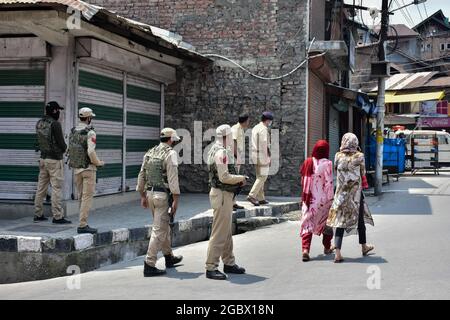 Le donne del Kashmiri camminano oltre le forze governative in piedi allerta dopo che un'esplosione ha avuto luogo vicino alla Grande Moschea il secondo anniversario dell'abrogazione dello status autonomo e della statehood a Srinagar.un'esplosione ha avuto luogo vicino alla Grande Moschea il giovedì, ma non sono state segnalate perdite di vite umane o lesioni, hanno detto i funzionari. Hanno detto che l'esplosione, sospettata di essere un dispositivo esplosivo improvvisato (IED), ha avuto luogo intorno a mezzogiorno. L'esplosione si è svolta nel secondo anniversario dell'abrogazione dello status autonomo e dello stato. (Foto di Saqib Majeed/SOPA Images/Sipa USA) Foto Stock