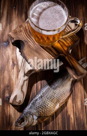 Birra con pesce secco e spuntini su tavola di legno. Foto Stock