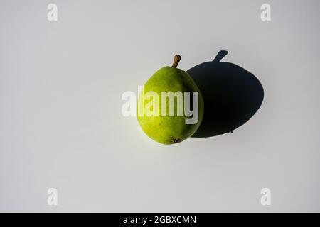Una pera e la sua ombra su uno sfondo bianco Foto Stock
