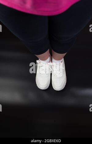 Germogli che indossano scarpe sportive/ Foots in posa per fare alcuni esercizi su sfondo nero. Foto Stock