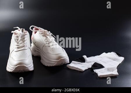 Sneakers bianche con calze preparate su sfondo nero per l'allenamento femminile. Foto Stock