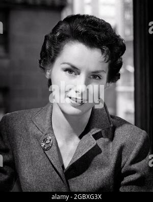 1950 DONNA SORRIDENTE PROFESSIONISTA CHE INDOSSA ABITO IN LANA CON BROOCH ALLA FINESTRA DI OFFICE GUARDANDO LA FOTOCAMERA - G2309 CLE003 HARS SODDISFATTO GIOIA STILE DI VITA FEMMINE STUDIO SHOT SALUBRITÀ GIOIELLI LANA COPIA SPAZIO SIGNORE PERSONE ESPRESSIONI B&W UOMO D'AFFARI OCCHIO CONTATTO FELICITÀ TESTA E. SPALLE ALLEGRO BROOCH STILI SOFISTICATI SORRISI FRANK COSMOPOLITA GIOIOSO ELEGANTE UOMINI D'AFFARI MODA COMPETENTE METÀ-ADULTO DONNA MEDIO-ADULTA GIOVANE DONNA ADULTA NERA E BIANCO ETNIA CAUCASICA CAPELLI CORTI VECCHIO STILE Foto Stock