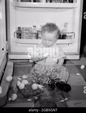 ANNI '50 INQUIETANTE BAMBINO RAGAZZO DISORDINATO SUL PAVIMENTO DELLA CUCINA DI FRONTE A UNA PORTA DI FRIGORIFERO APERTO GIOCO CON VASSOIO DI ROTTO UOVA - J3602 HAR001 HARS COPIA SPAZIO FULL-LENGTH MASCHI INTRATTENIMENTO B&W ROTTURA TENTAZIONE DISASTRO ALTO ANGOLO AVVENTURA SCOPERTA ECCITAZIONE DISORDINATA RICREAZIONE IN SU CONCETTUALE ELEGANTE BAMBINO RAGAZZO CREATIVITÀ GIOVANILE NERO E BIANCO CAUCASICO ETNIA HAR001 VECCHIO STILE Foto Stock