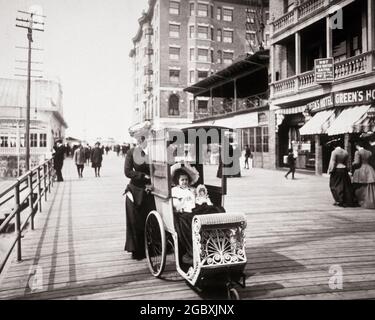 MADRE DEL 1890 O NANNY CHE SPINGE IL CARRELLO ELABORATO DEL VIMINI CHE TIENE LA SUA RAGAZZA DELLA FIGLIA E LA SUA BAMBOLA SUL BOARDWALK DELLA CITTÀ ATLANTICA NJ USA - KO4262 NAW001 HARS BEAUTY COMMUNITY CARRELLO URBANO SUBURBANO LE SUE MADRI VECCHIO TEMPO OCCUPATO NOSTALGIA VECCHIO MODO 1 ATLANTICO GIOVANE ADULTO GIOVANE VACANZA PASSEGGINO GIOIA STILE DI VITA STORIA FEMMINE BENESSERE LUSSO STATI UNITI COPIA SPAZIO FULL-LENGTH DONNE NANNY FIGLIE PERSONE WICKER STATI UNITI D'AMERICA CARING ENTERTAINMENT TRASPORTO PASSERELLA B&W NORD AMERICA NORD AMERICA TEMPO OFF GRANDANGOLO FELICITÀ BENESSERE PROTEZIONE PER IL TEMPO LIBERO Foto Stock