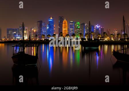 Doha, Qatar - 29 settembre 2019: Skyline illuminato di Doha di notte con le tradizionali barche in legno chiamate Dhows in primo piano, Qatar, mi Foto Stock