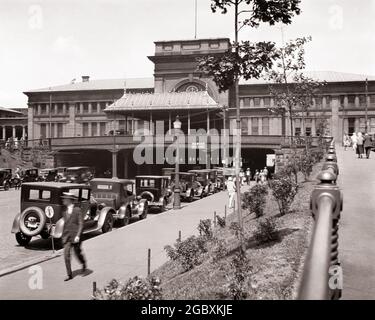 1910 ANNI 1920 STAZIONE FERROVIARIA DI FRONTE A PEDONI PIAZZA UFFICIO POSTALE E STRADA PASSANDO SOTTO LA STAZIONE PROVIDENCE RHODE ISLAND USA - Q19031 CPC001 HARS SIGNORE PERSONE STATI UNITI D'AMERICA AUTOMOBILE MASCHI PEDONI TRASPORTO B&W PARCHEGGIATO NORD AMERICA GRANDANGOLO NORDAMERICANO PASSAGGIO E AUTOS ESTERNO RHODE ISLAND CONNESSIONE CONCETTUALE AUTOMOBILI ELEGANTI VEICOLI RI PROVIDENCE BIANCO E NERO VECCHIO STILE UFFICIO POSTALE Foto Stock