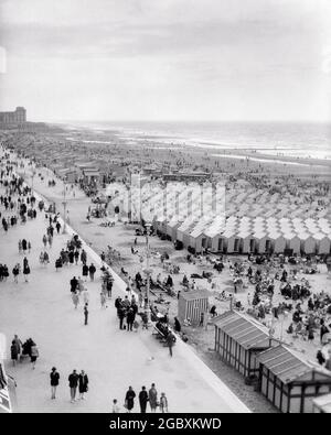 1920 BAGNI E BEACH BOX SULLA SPIAGGIA DI SABBIA E LE PERSONE CHE PASSEGGIANO SUL LUNGOMARE OSTENDA BELGIO - R4433 HAR001 HARS PEDONE ALTO ANGOLO AVVENTURA EUROPEA VIAGGIO DI PIACERE E FUGA DIVERTIMENTO DIVERTIMENTO SPIAGGE BELGHE VACANZE PASSEGGIATE CITTÀ LUNGOMARE VACANZE SABBIOSE BIANCO E NERO FIAMMINGO HAR001 VECCHIO STILE Foto Stock