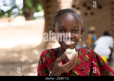 In questa immagine, una ragazza africana nera astuta sta mangiando un uovo bollito con grande delizia Foto Stock