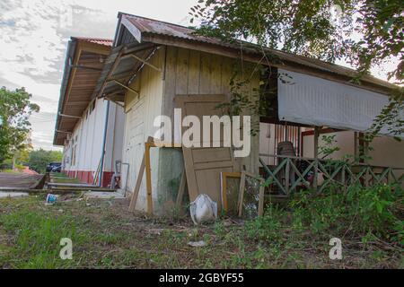 Vista esterna di un magazzino polveroso e abbandonato con porta, sedia, finestra e armadio rotti Foto Stock