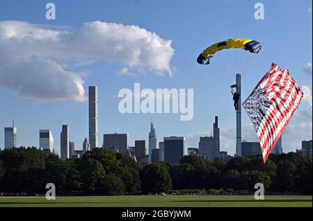 New York City, Stati Uniti. 05 agosto 2021. Lo skyline di Manhattan è visto dietro un membro della squadra di paracadute della marina degli Stati Uniti "Leap Frogs" mentre vola una bandiera degli Stati Uniti durante il suo atterraggio sul Great Lawn in Central Park, New York, NY, 5 agosto 2021. La squadra di paracadute US Navy Leap Frog è iniziata nel 1969 e ha il compito di "dimostrare l'eccellenza della Marina in tutti gli Stati Uniti". (Anthony Behar/Sipa USA) Credit: Sipa USA/Alamy Live News Foto Stock