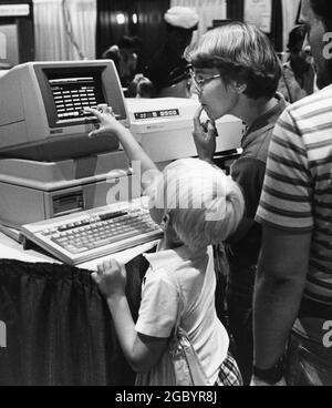 Austin, Texas USA, circa 1986: Il giovane ragazzo controlla il nuovo personal computer mentre la madre guarda alla fiera della tecnologia. ©Bob Daemmrich Foto Stock