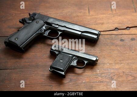 Pistole su sfondo di legno. Due armi in metallo nero, pistole automatiche per la protezione e attacco su un tavolo vintage. Vista laterale Foto Stock