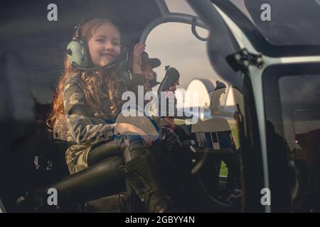 Sorridente presetino ragazza in cuffia pilota con amico in elicottero cockpit Foto Stock