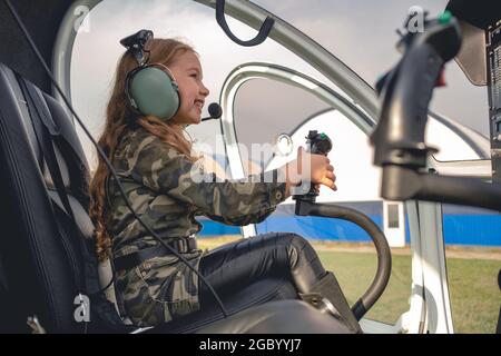 Sorridente ragazza in cuffia aviatore seduto nell'abitacolo dell'elicottero Foto Stock