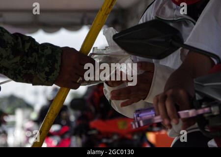 Filippine. 06 agosto 2021. I membri della polizia della città di Quezon ispezionano le identificazioni degli automobilisti ad un confine tra Rizal e Quezon City durante il primo giorno della quarantena della comunità potenziata (ECQ) il 6 agosto 2021. La Regione capitale Nazionale (NCR), per la terza volta è posta sotto ECQ - - la più rigorosa classificazione di quarantena nel paese per due settimane o fino all'agosto 20. Durante l'ECQ, solo le persone autorizzate al di fuori del Residence (APOR) possono viaggiare all'interno e all'esterno dell'NCR. (Foto di Larry Monserate Piojo/Sipa USA) Credit: Sipa USA/Alamy Live News Foto Stock