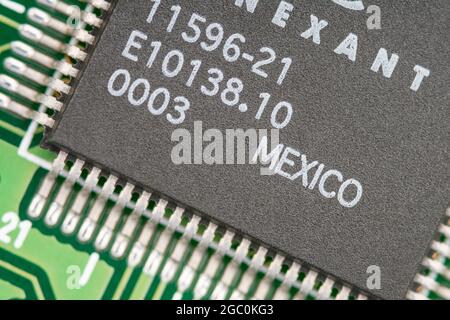 Macro primo piano di un microchip realizzato in Messico su una scheda modem legacy pcb con righe di piedini visibili. Chip realizzato da Conexant. Foto Stock