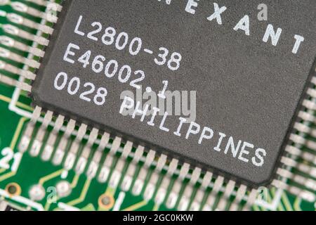 Macro primo piano di un microchip realizzato in Filippine su una scheda modem legacy pcb con righe di piedini visibili. Chip realizzato da Conexant. Foto Stock