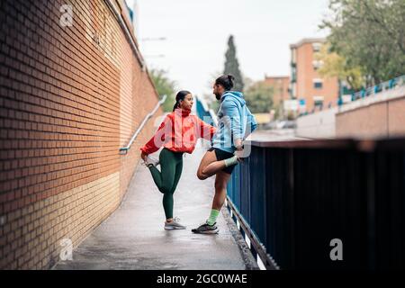 Giovani amici che indossano abiti sportivi che si allungano dopo l'esercizio durante la giornata piovosa. Foto Stock