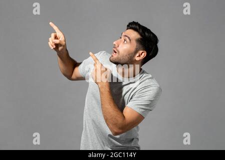 Scioccato giovane uomo caucasico che spadaccava con le mani puntando su isolato sfondo grigio chiaro studio Foto Stock