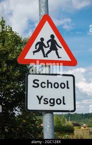 Cartello di avvertimento bilingue per l'attraversamento delle scuole in lingua gallese e inglese nelle zone rurali del Galles del Nord Regno Unito Foto Stock