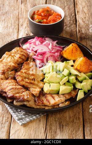 Il POC Chuc è un piatto messicano di carne di maiale, preparato in marinata di agrumi e cotto su una griglia servita con cipolla sottaceto e avocado in primo piano Foto Stock