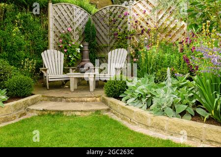 Bellissimo giardino privato paesaggistico colorato (design contemporaneo, linee di confine curve, chiminea ornamentale, recinzione, terrazzamento) - Yorkshire Inghilterra UK Foto Stock