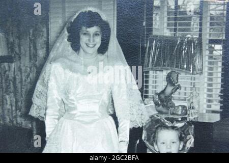 Una vecchia foto di una giovane donna sorridente mentre indossa il suo vestito da sposa. Foto Stock