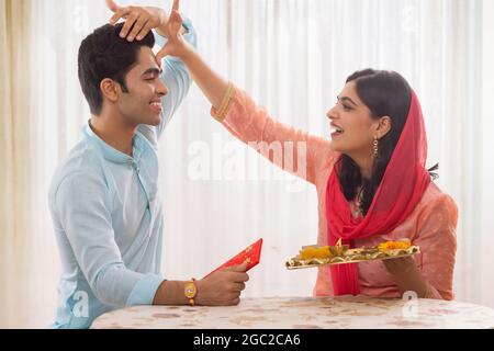 FRATELLI FELICI CHE SEGUONO GIOCOSAMENTE I RITUALI SU RAKSHABANDHAN Foto Stock