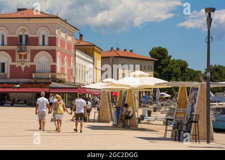 Porec, Croazia - 10 luglio 2021. I venditori ambulanti che vendono gite in barca sul lungomare aspettano i clienti nella storica cittadina costiera medievale di Porec Foto Stock