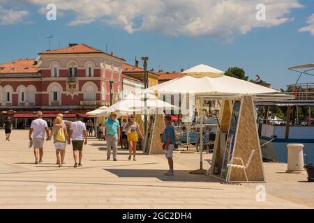Porec, Croazia - 10 luglio 2021. I venditori ambulanti che vendono gite in barca sul lungomare aspettano i clienti nella storica cittadina costiera medievale di Porec Foto Stock